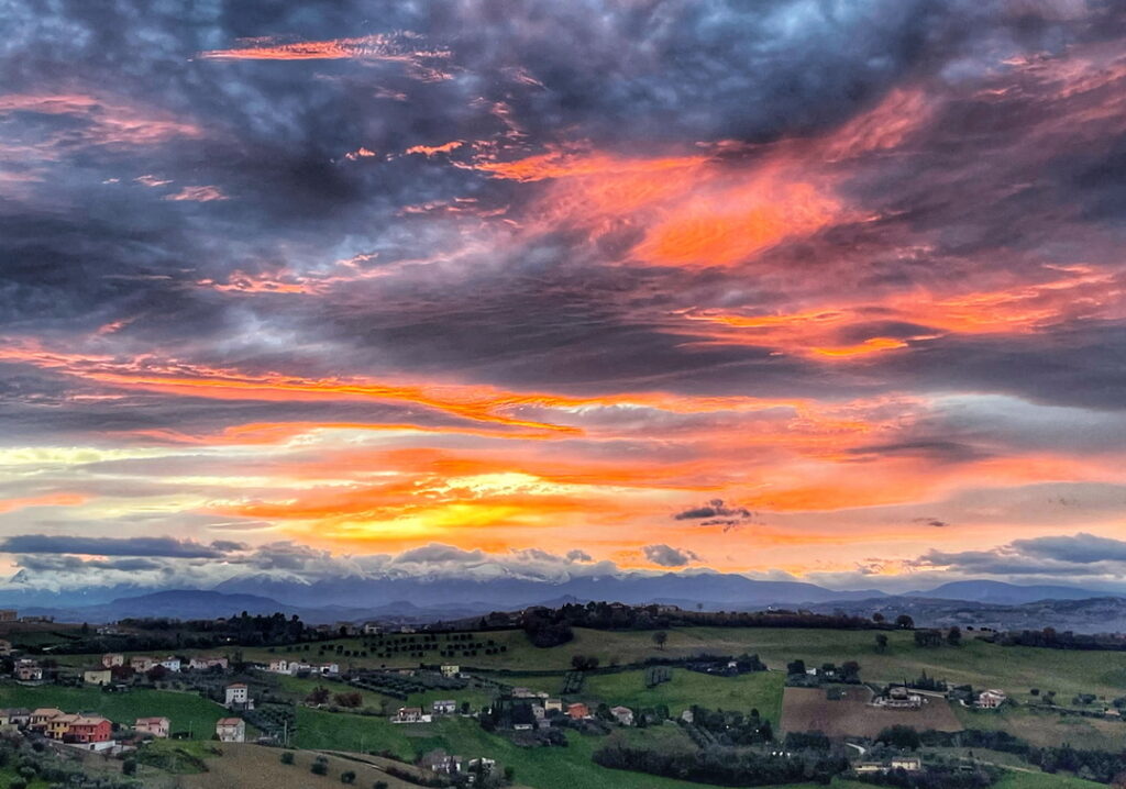 Dramatischer Sonnenuntergang mit orange-roten
Wolken über den Dächern von Fermo, Marken, Italien